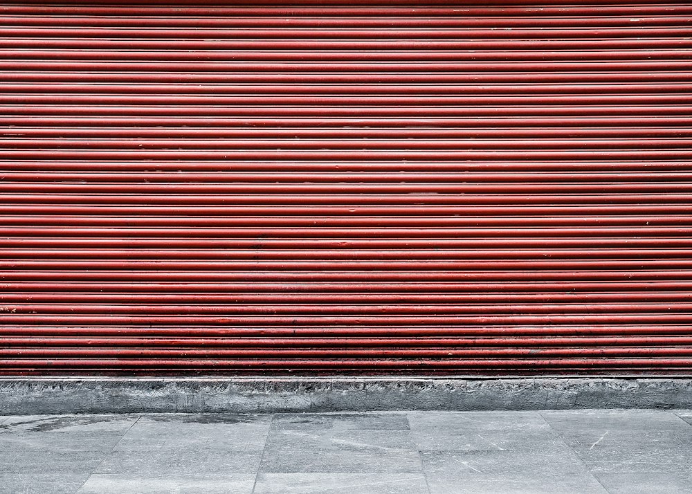 Cortina metálica roja cerrada en el frente de un local